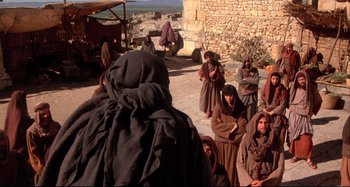 Movie still from “The Last Temptation of Christ” (1988), directed by Martin Scorsese – A group of people sitting on the side of a road; Wide shot, Over the shoulder angle