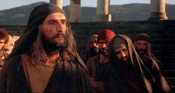 Movie still from “The Last Temptation of Christ” (1988), directed by Martin Scorsese – A group of men standing next to each other in front of a building; Medium shot, Low angle