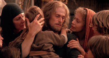 Movie still from “The Last Temptation of Christ” (1988), directed by Martin Scorsese – A man and two women hug while holding a young child; Close Up shot, Over the shoulder angle