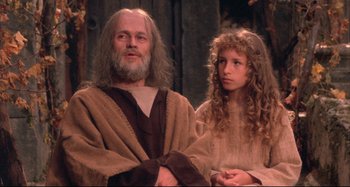 Movie still from “The Last Temptation of Christ” (1988), directed by Martin Scorsese – An old man and a young girl are sitting next to each other; Medium shot, Low angle