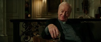 Movie still from “The Last Witch Hunter” (2015), directed by Breck Eisner – An older man sitting in a chair holding a glass of whiskey; Close Up shot, Over the shoulder angle