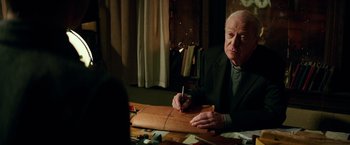 Movie still from “The Last Witch Hunter” (2015), directed by Breck Eisner – An older man sitting at a table writing on a piece of paper; Close Up shot, High angle
