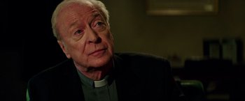 Movie still from “The Last Witch Hunter” (2015), directed by Breck Eisner – An older man wearing a priest's collar; Close Up shot, Over the shoulder angle