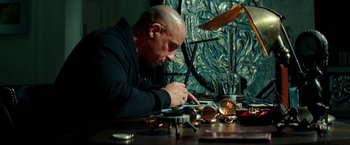 Movie still from “The Last Witch Hunter” (2015), directed by Breck Eisner – A man sitting at a table working on a clock; Medium shot, High angle