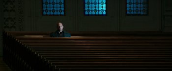 Movie still from “The Last Witch Hunter” (2015), directed by Breck Eisner – A man sitting alone in a church with stained glass windows; Wide shot, Low angle