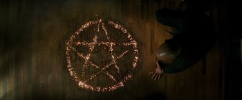 Movie still from “The Last Witch Hunter” (2015), directed by Breck Eisner – A person sitting on the ground with a pentagram drawn in the middle of the floor; Extreme Close Up shot, Overhead angle