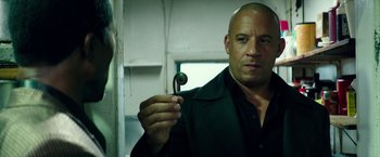 Movie still from “The Last Witch Hunter” (2015), directed by Breck Eisner – A man in a black shirt holding a pipe; Close Up shot, Over the shoulder angle