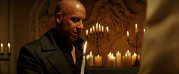 Movie still from “The Last Witch Hunter” (2015), directed by Breck Eisner – A bald man holding a lit candle in front of a chandelier; Close Up shot, Over the shoulder angle