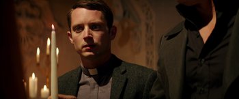 Movie still from “The Last Witch Hunter” (2015), directed by Breck Eisner – A man wearing a priest's collar stands in front of a wall; Close Up shot, Over the shoulder angle