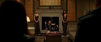 Movie still from “The Last Witch Hunter” (2015), directed by Breck Eisner – A man sitting in front of two women in front of a fireplace; Wide shot, High angle