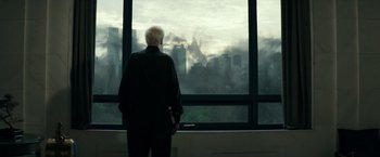 Movie still from “The Last Witch Hunter” (2015), directed by Breck Eisner – An older man standing in front of a large window; Wide shot, Over the shoulder angle