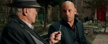 Movie still from “The Last Witch Hunter” (2015), directed by Breck Eisner – A bald man holding a screwdriver talking to a man in a suit; Close Up shot, Over the shoulder angle