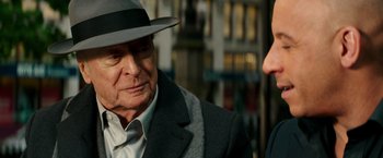 Movie still from “The Last Witch Hunter” (2015), directed by Breck Eisner – An older man wearing a hat and a suit; Close Up shot, Over the shoulder angle