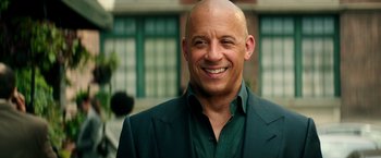Movie still from “The Last Witch Hunter” (2015), directed by Breck Eisner – A man in a green suit smiling for the camera; Close Up shot, Over the shoulder angle