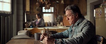 Movie still from “Rambo: Last Blood” (2019), directed by Adrian Grunberg – A man and a woman in a kitchen with pots and pans on the counter; Medium shot, Over the shoulder angle