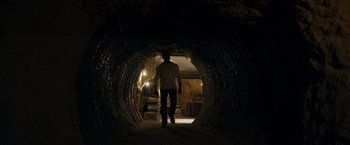 Movie still from “Rambo: Last Blood” (2019), directed by Adrian Grunberg – A man walking through a tunnel in the dark; Wide shot, Low angle