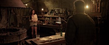 Movie still from “Rambo: Last Blood” (2019), directed by Adrian Grunberg – A woman standing next to a man in a room filled with furniture; Wide shot, Over the shoulder angle