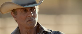 Movie still from “Rambo: Last Blood” (2019), directed by Adrian Grunberg – An older man wearing a hat and a plaid shirt; Close Up shot, Over the shoulder angle