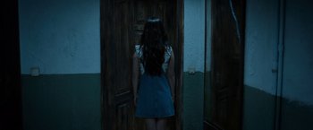 Movie still from “Rambo: Last Blood” (2019), directed by Adrian Grunberg – A woman standing in front of a wooden door; Medium shot, Over the shoulder angle