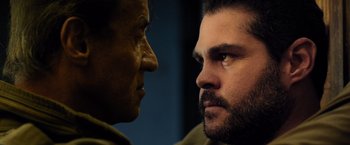 Movie still from “Rambo: Last Blood” (2019), directed by Adrian Grunberg – A man stares at another man's face in the dark; Close Up shot, Over the shoulder angle