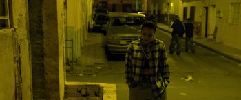 Movie still from “Rambo: Last Blood” (2019), directed by Adrian Grunberg – A person standing on a city street at night; Medium shot, High angle