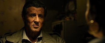 Movie still from “Rambo: Last Blood” (2019), directed by Adrian Grunberg – A man in a green jacket is looking at the camera; Close Up shot, Low angle