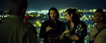 Movie still from “Rambo: Last Blood” (2019), directed by Adrian Grunberg – Two men standing next to each other on a city street; Medium shot, Over the shoulder angle