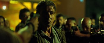 Movie still from “Rambo: Last Blood” (2019), directed by Adrian Grunberg – A person wearing a shirt; Close Up shot, Over the shoulder angle