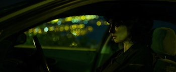 Movie still from “Rambo: Last Blood” (2019), directed by Adrian Grunberg – A person sitting in a car at night with lights in the background; Close Up shot, Over the shoulder angle