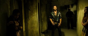 Movie still from “Rambo: Last Blood” (2019), directed by Adrian Grunberg – A man standing in a dark room holding a gun; Medium shot, Low angle