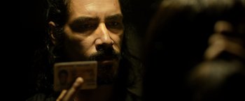 Movie still from “Rambo: Last Blood” (2019), directed by Adrian Grunberg – A man with long hair and a beard is holding a card; Close Up shot, Over the shoulder angle
