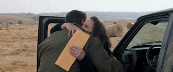 Movie still from “Rambo: Last Blood” (2019), directed by Adrian Grunberg – A man and a woman hugging in the back of a car; Medium shot, High angle