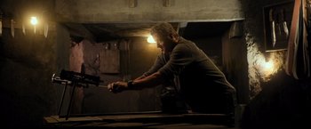 Movie still from “Rambo: Last Blood” (2019), directed by Adrian Grunberg – A man in a dark room holding a metal object; Medium shot, Low angle
