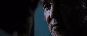 Movie still from “Rambo: Last Blood” (2019), directed by Adrian Grunberg – An older man's face is lit up by the light; Extreme Close Up shot, Over the shoulder angle