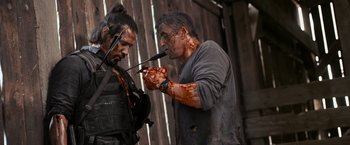 Movie still from “Rambo: Last Blood” (2019), directed by Adrian Grunberg – A man with a knife in his mouth and another man with a knife in his other hand; Close Up shot, Over the shoulder angle