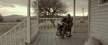 Movie still from “Rambo: Last Blood” (2019), directed by Adrian Grunberg – A man sitting in a rocking chair on a porch; Wide shot, Low angle