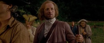 Movie still from “The Last of the Mohicans” (1992), directed by Michael Mann – A man with long red hair wearing a brown jacket; Medium shot, Over the shoulder angle