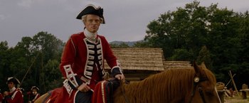 Movie still from “The Last of the Mohicans” (1992), directed by Michael Mann – A man dressed in a red and black uniform riding on a horse; Medium shot, Low angle