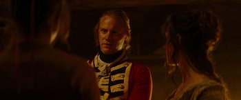 Movie still from “The Last of the Mohicans” (1992), directed by Michael Mann – A man in a red and black jacket standing in a room; Close Up shot, Over the shoulder angle