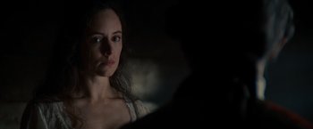 Movie still from “The Last of the Mohicans” (1992), directed by Michael Mann – A woman is looking at the camera in the dark; Close Up shot, Over the shoulder angle