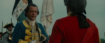 Movie still from “The Last of the Mohicans” (1992), directed by Michael Mann – A man in a red jacket and a man in a blue and yellow jacket; Close Up shot, Over the shoulder angle