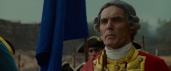 Movie still from “The Last of the Mohicans” (1992), directed by Michael Mann – A man in a period costume stands in front of a flag; Close Up shot, Low angle