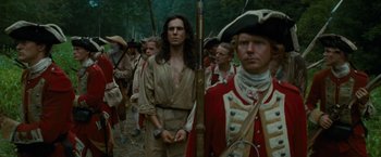 Movie still from “The Last of the Mohicans” (1992), directed by Michael Mann – A group of men in period clothing standing next to each other; Medium shot, Over the shoulder angle