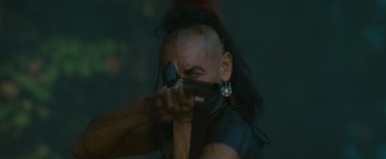 Movie still from “The Last of the Mohicans” (1992), directed by Michael Mann – A man with a mohawk is holding a gun in his hand; Close Up shot, Over the shoulder angle