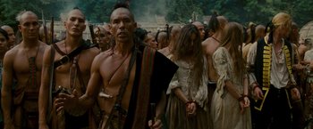 Movie still from “The Last of the Mohicans” (1992), directed by Michael Mann – A group of native americans gathered together in the woods; Medium shot, Over the shoulder angle