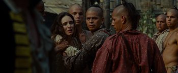 Movie still from “The Last of the Mohicans” (1992), directed by Michael Mann – A group of men standing around a woman in a forest; Close Up shot, Over the shoulder angle