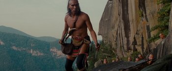 Movie still from “The Last of the Mohicans” (1992), directed by Michael Mann – A man in native american garb walking on a cliff; Medium shot, Low angle