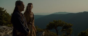 Movie still from “The Last of the Mohicans” (1992), directed by Michael Mann – A man standing on top of a hill next to a tree; Medium shot, Low angle