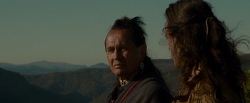 Movie still from “The Last of the Mohicans” (1992), directed by Michael Mann – A man with a long black hair and an ear piercing; Close Up shot, Over the shoulder angle