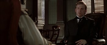 Movie still from “The League of Extraordinary Gentlemen” (2003), directed by Stephen Norrington – A man sitting in a chair in a living room; Medium shot, Over the shoulder angle